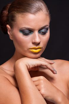 woman with extreme colorfull make up in blue and yellow on black background