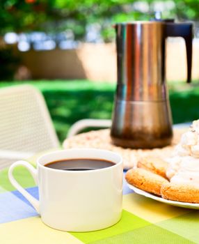 Coffee cup with cookies and moka pot outdoors