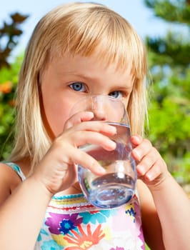 Cute little girl drinking water outdoors