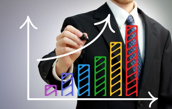 Businessman drawing a rising arrow over a colorful bar graph