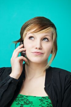 young woman chatting on a cell phone over a green wall