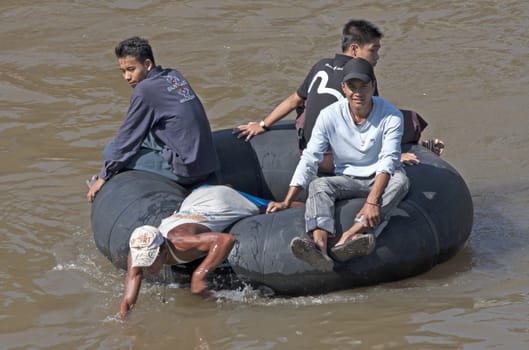 MAE SOT, THAILAND NOV 12TH: Burmese crossing the Moei river on an innertube on Nov 12th 2009. Many Burmese cross the river between Myanmar and Thailand illegally to work in Thailand.