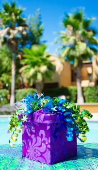 Purple Gift box with ribbon by the swimming pool
