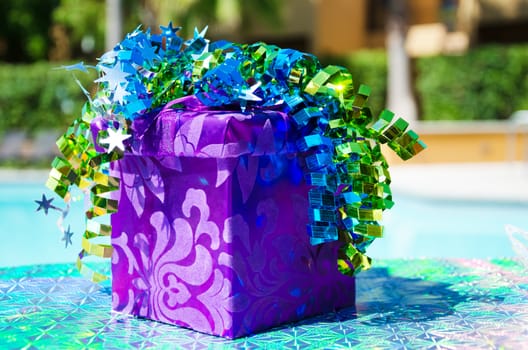 Purple Gift box with ribbon by the swimming pool