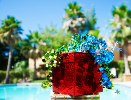 Red Gift box with ribbon by the swimming pool 