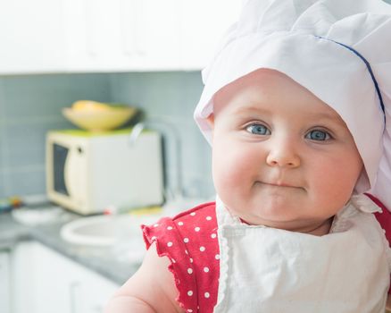 little cute baby with a chef's hat in the kitchen