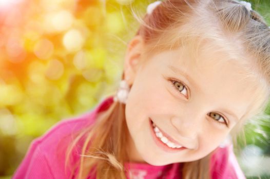 beautiful cute little girl smiling in a park close-up