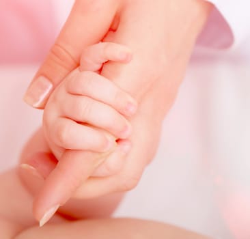 Closeup of baby's hand holding mother's finger
