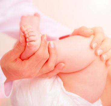 Mother's hands massaging her little baby's foot