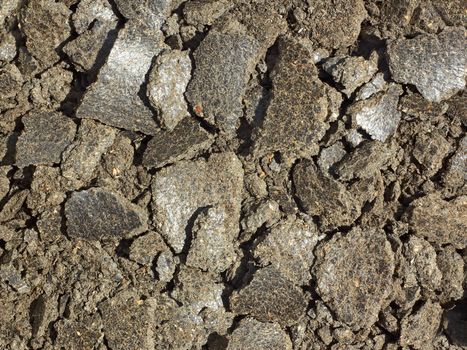 Shapeless pieces of oil cake in the heap close up. It is used as feed for animals, birds and fish