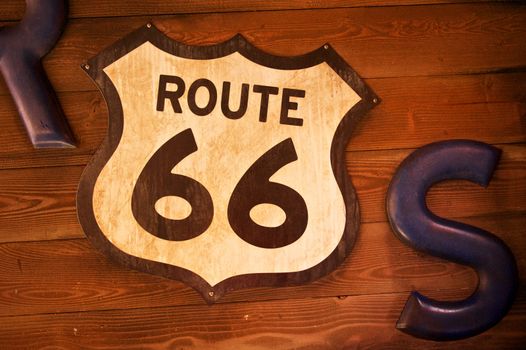 Old and rusty route 66 sign hangs on a wall made of wooden planks