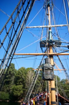 An old rusted and weathered lamp hangs from a rope on an old-fashioned sailing ship