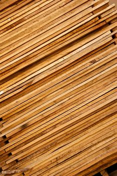 Stack of thin, rough cut wood lumber with signs of aging from being left outside