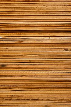 Stack of thin, rough cut wood lumber with signs of aging from being left outside