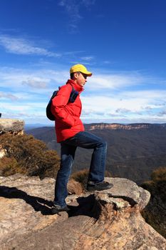 A bushwalker hiker looks out at views to Kings Tableland and Jamison Valley from Flat Rock Blue Mountains Australia
