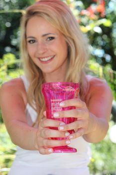 Smiling blond woman holding a red glass in a close up shot