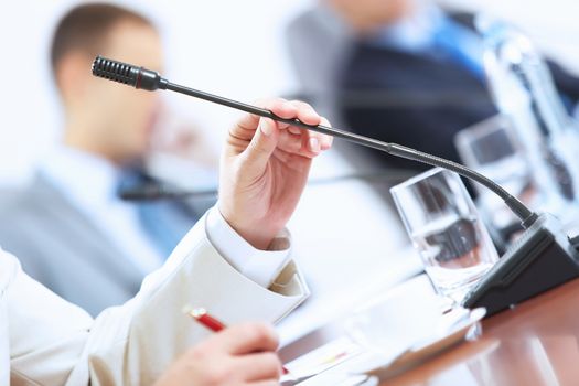 Image of businessman's hands holding microphone at conference