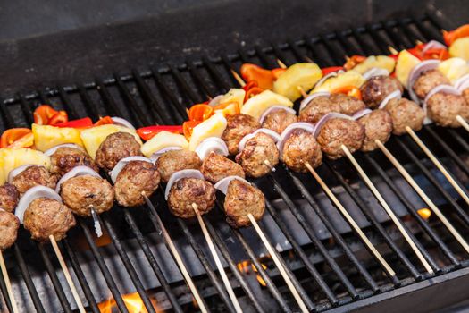 Delicious meatballs and pieces of pineapple, peppers and onion on skewers.