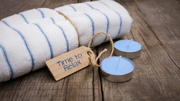 A towel with a sign and candles on wooden background