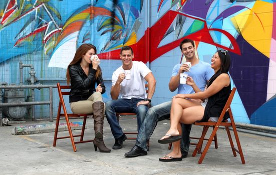 Four friends sitting together during a brake drinking coffee.