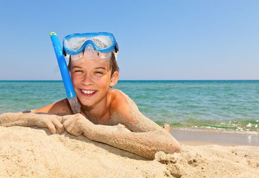 Happy boy wearing snorkeling gear relaxing on the beach