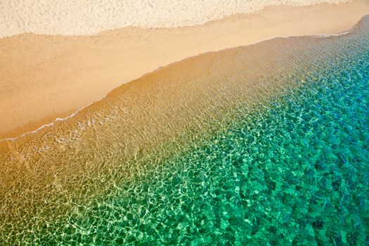Turquoise water washing up onto sandy beach in Sardinia