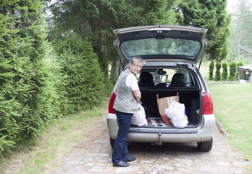 A retired pensior loading shopping bags from boot of car, real people candid shot