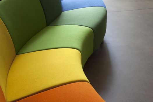 Detail of a curved sofa in green, orange and yellow