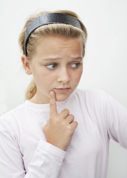 A girl holding a finger to her cheek looking worried