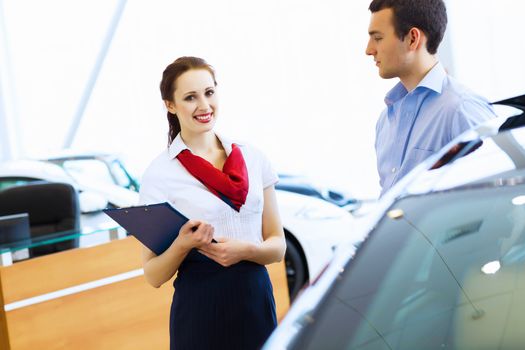 Young man choosing car at salon with help of consultant