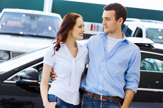 Two pretty young people smiling standing near car