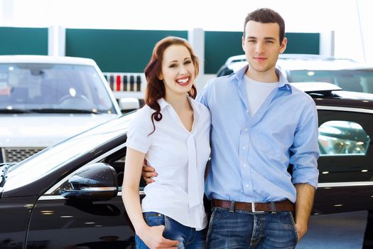 Two pretty young people smiling standing near car