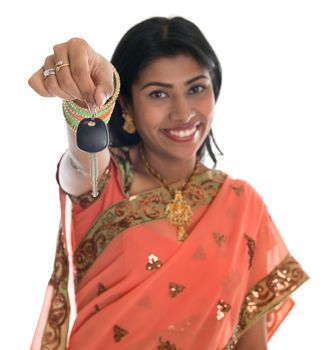 Attractive traditional Indian woman in sari holding her first own car key isolated on white background. Focus on car key.