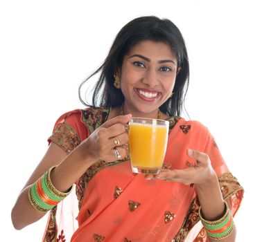 Happy traditional Indian woman in sari drinking a glass of orange juice, isolated on white background.