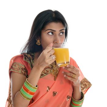 Traditional Indian woman in sari drinking orange juice, isolated on white background.