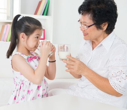 Drinking milk. Happy multi generations Asian family at home. Beautiful grandmother and granddaughter, healthcare concept.
