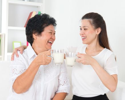 Drinking milk. Asian family drinking milk at home. Beautiful senior mother and adult daughter, healthcare concept.
