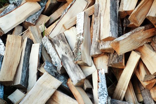 Firewood, prepared for the fireplace, lay a heap on the ground.
