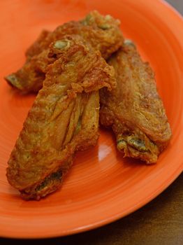 tasty fried chicken wings on an orange plate