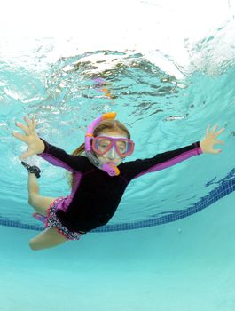 kid swimming underwater in summer in a pool
