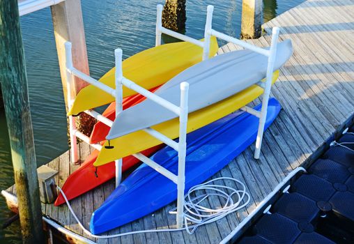 Group of colorful kayaks stacked on dock