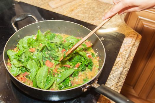 Frying spinach leaves on a large metal pan.