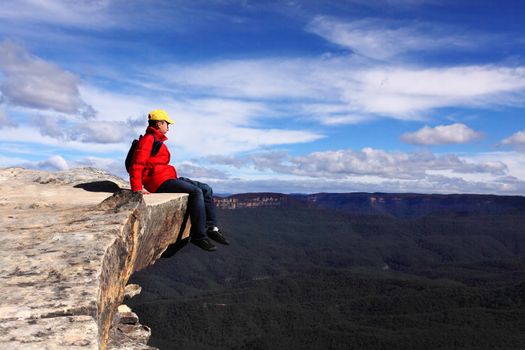 Sitting on Top of the World - hiker rests and admires views of Blue Mountains on a beautiful sunny day.  Selective focus.