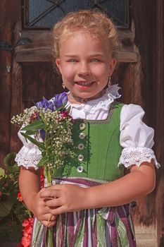 Portrait of a little girl in dirndl with a bouquet