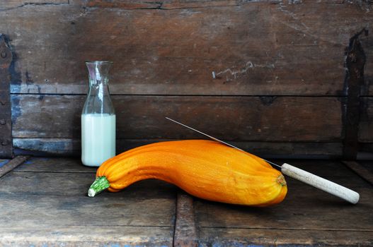 Yellow squash with knife and milk in a rustic kitchen