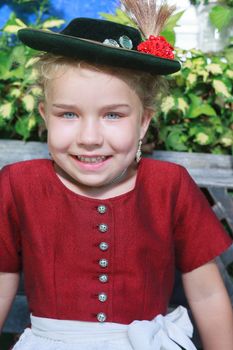 Portrait of a little smiling girl with hat in traditional Bavarian dirndl