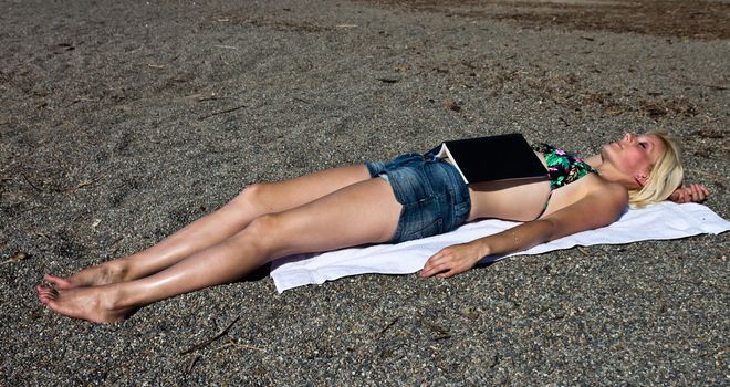 Young woman with a book sleeping on the beach