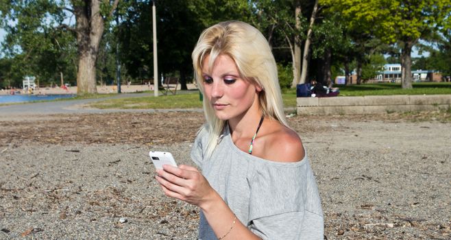 Young woman on the beach using a smart phone