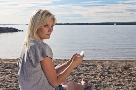 Young woman on the beach using a smart phone