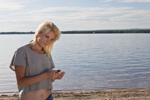 Young woman on the beach using a smart phone